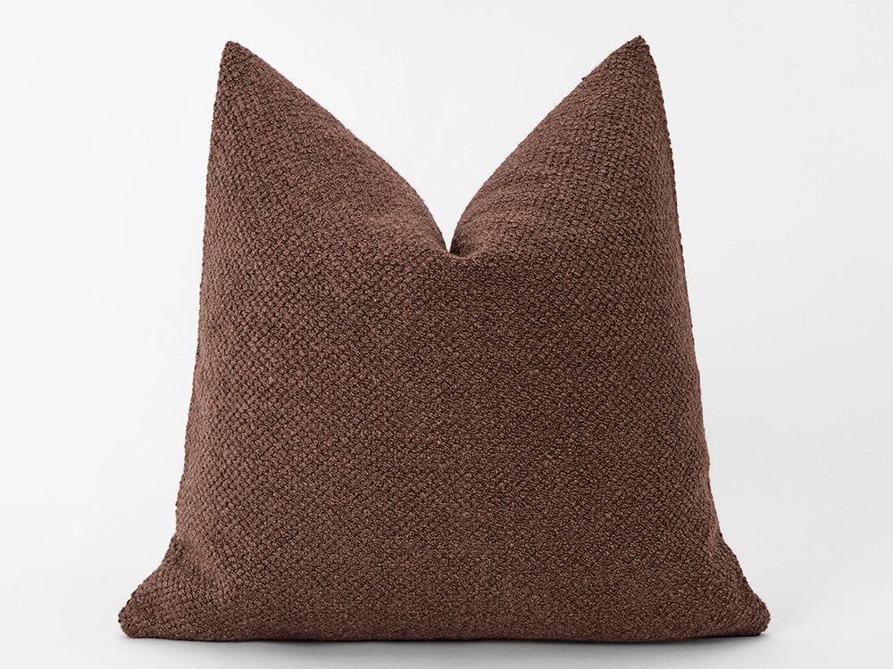 A square-shaped pillow cover with a deep cognac hue and a soft boucle texture.